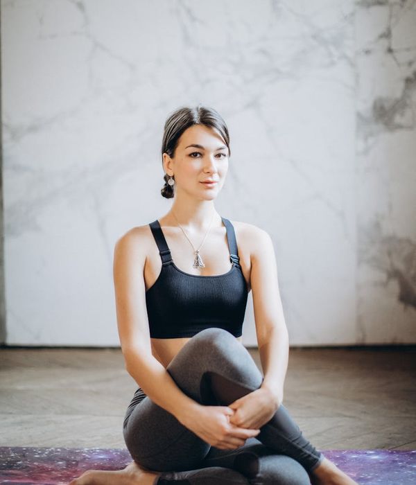 Woman in a calm yoga pose against a dark, serene background.